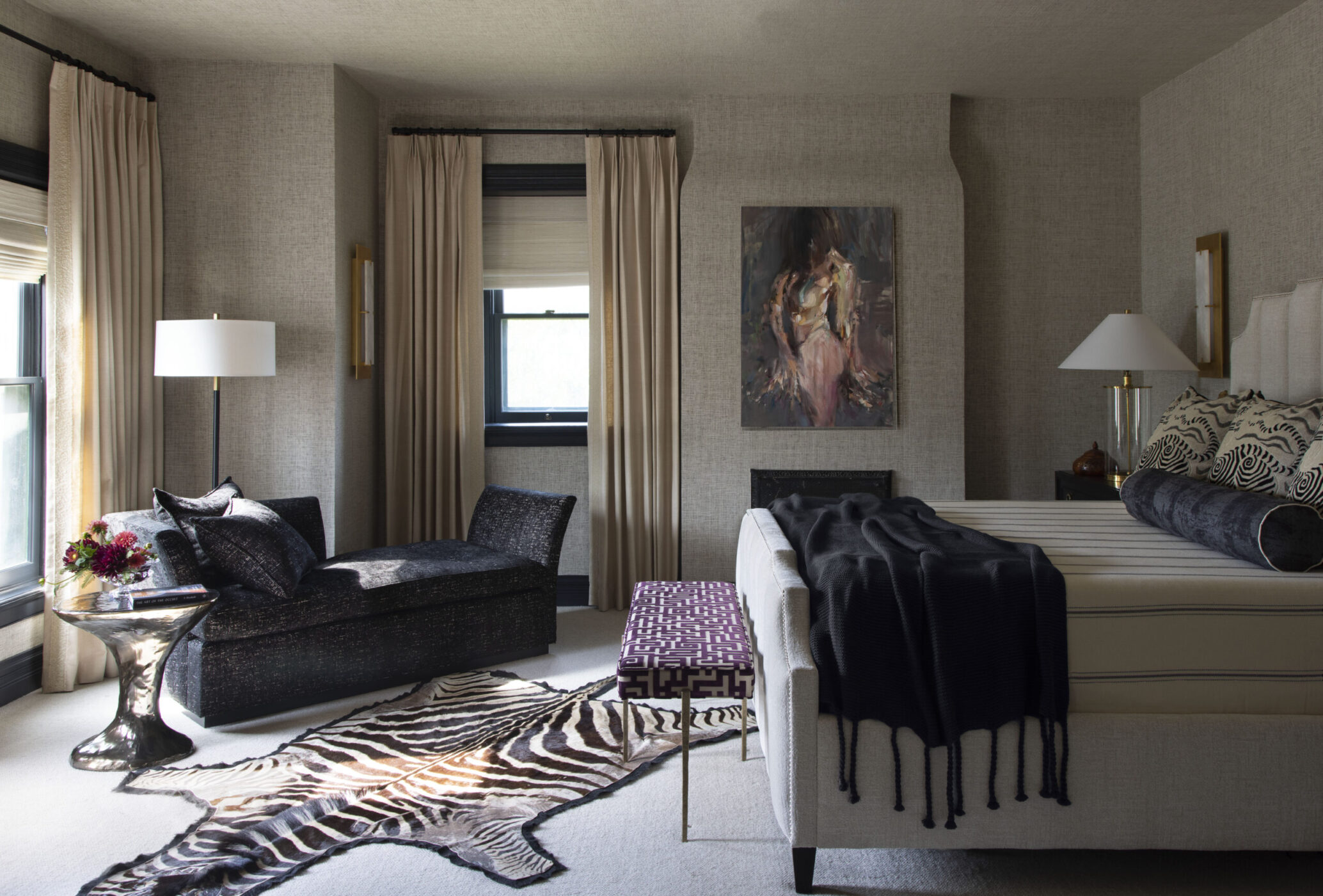 Rivington Marx Interiors Bedroom Scene bedroom Luxury interior design with upholstered walls, a black chaise lounge, zebra hide rug, and brass accents.